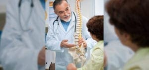 A doctor showing a child how to use an artificial spine.