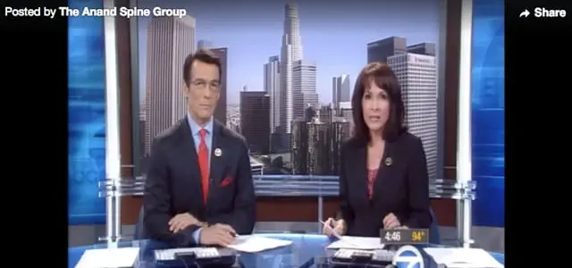 Two people are sitting at a news desk.