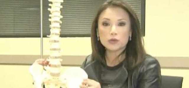 A woman sitting in front of a model of a human spine.