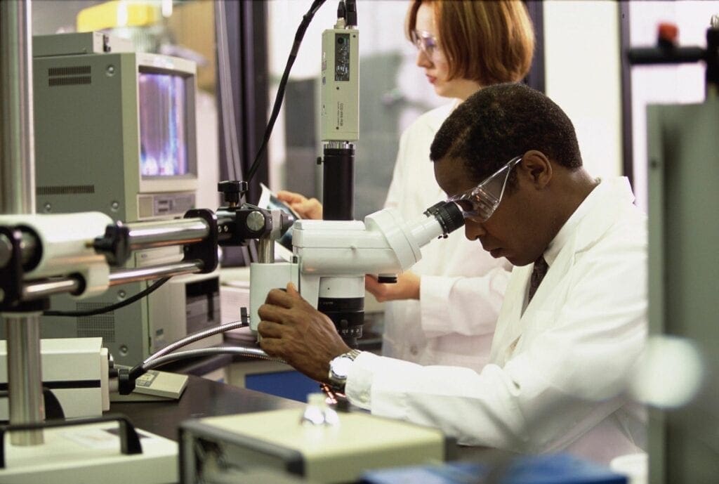 A man working in a lab with another person.