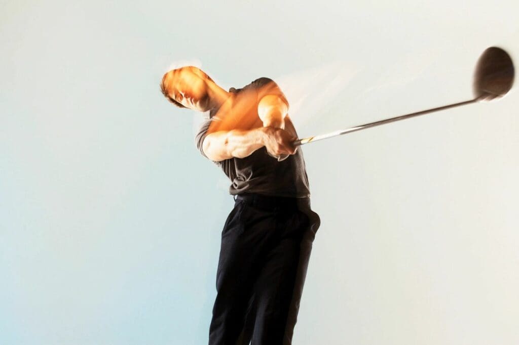 A man swinging at the end of his golf swing.