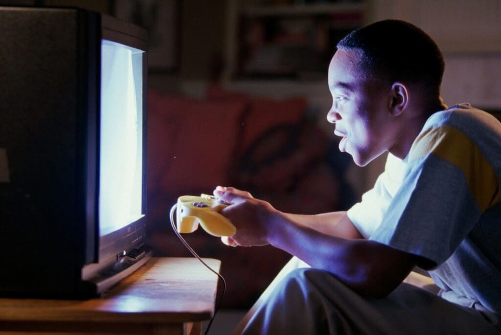 A man sitting in front of a computer holding a game controller.