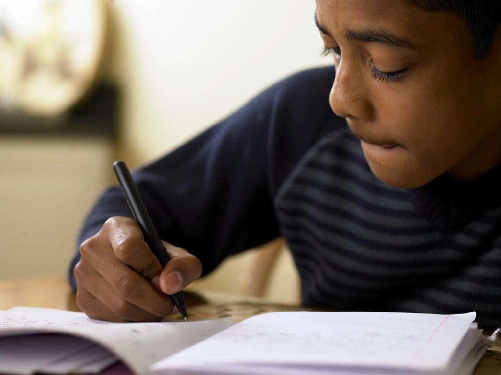 A boy is writing in his notebook