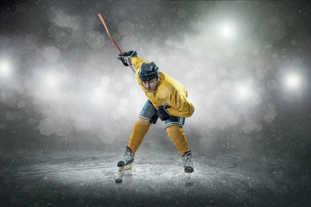 A hockey player in yellow and blue is holding a stick.