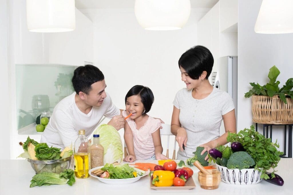 A family is sitting at the table with vegetables.