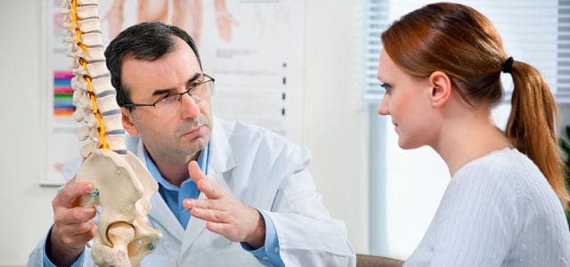 A doctor helping a patient who needs motion preservation surgery.